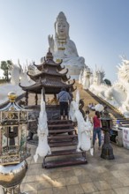 Visitors make a wai phra offering to Buddah in front of the Guan Yin (Goddess of Mercy) statue at