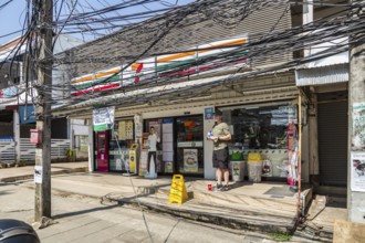 American tourist standingunder a tangled mess of utility wires outside a 7 Eleven store in Chiang