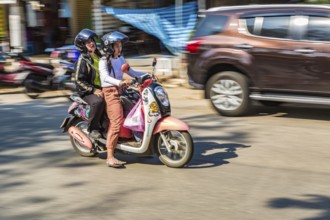 Thai women riding a scooter along Ban Du street in Chiang Rai, Thailand