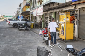 Thai man filling motor scooter with gasoline from a remote Sun Oil pump in Chiang Rai, Thailand
