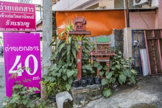Buddahist shrine outside of a business on the sidewalk in Chiang Rai province of Northern Thailand
