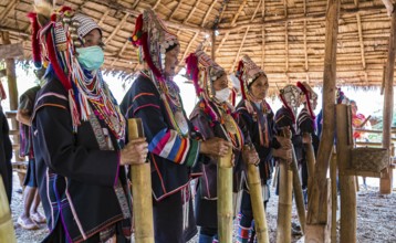 Elderly traditionally dressed people perform a musical chant for a fee in the Akha tribe area of