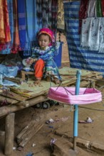 Tribal child spooling yarn for weaving scarves to be sold in the Long Neck Karen tribe (more