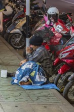 Homeless woman and son begging for money on the downtown street at night in Chiang Rai, Thailand