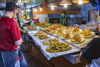 Customers looking over choices of fresh fried seafood at the night market in downtown Chiang Rai,