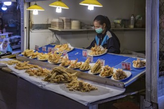 Thai street vendor offers fresh fried seafood at the night market in downtown Chiang Rai, Thailand