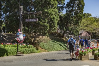 American tourists walking past a sign pointing to the entrance to the Doi Tung Royal Villa inside