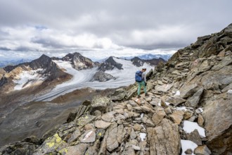Mountaineer with helmet on a rocky hiking trail, in high mountain landscape, view of blue glacial