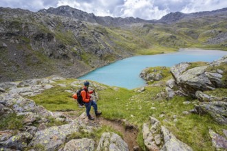 Mountaineers on a hiking trail, view of light blue mountain lake Trüber See in barren mountain