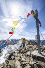 Mountaineers at the summit of Böses Weibl with summit cross and colourful prayer flags, view of