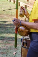 Woman playing an instrument of African origin called a berimbau outdoors, Minas Gerais, Brazil