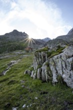 Mountain hut Elberfelderhütte in front of a rocky mountain landscape, sun star in the morning, in