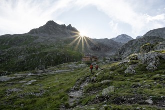 Mountaineer in front of mountain hut Elberfelderhütte with rocky mountain landscape, sun star in