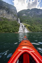 Kayak trip on the Geirangerfjord at the Freier waterfall, tip of a red kayak in the fjord,