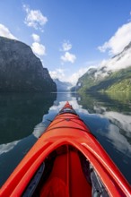 Kayak trip on the Geirangerfjord, tip of a red kayak in the fjord with reflection, atmospheric
