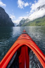 Kayak trip on the Geirangerfjord, tip of a red kayak in the fjord with reflection, atmospheric