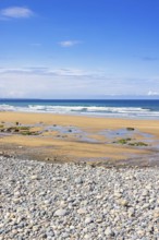 Pebble beach by the sea with a seascape view to the horizon and breaking waves on the shore a sunny