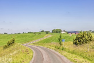 Winding gravel road in the countryside a sunny summer day with passing place road sign, Sweden