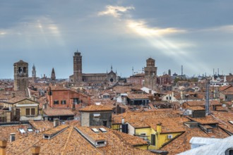 Stunning cityscape of venice with terracotta rooftops, churches, and sun rays piercing through