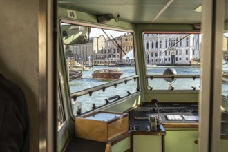 View from inside a vaporetto cockpit navigating grand canal in venice, with traditional venetian
