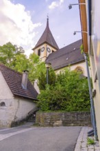 Gothic church with clock tower and surrounding trees, next to a wall, Deufringen, Aidlingen,