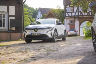 White car on a cobbled street in a picturesque village with half-timbered houses, Renault Megane,
