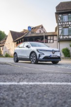 Modern car on an urban street, surrounded by historic half-timbered houses in the warm evening