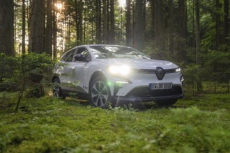White car standing in the sunlight in the green forest, Renault Megane, Deer E Carsharing, electric