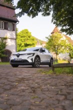 White car on cobblestones in a picturesque village, Renault Megane, Deer E Carsharing, electric