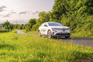 Renault car on a road, surrounded by green trees and meadows, Renault Megane, Deer E Carsharing,