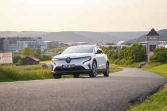 Car driving on a curvy road with modern city view in the background, Renault Megane, Deer E-