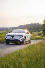 White car driving on a country road in the evening sunshine, Renault Megane, Deer E- Carsharing,