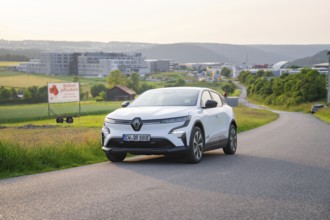 White car parked on a country road with hills and city view in the background, Renault Megane, Deer