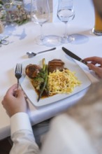 A gourmet plate with meat, asparagus and spaetzle on a festively laid table, event and wedding