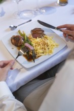 A plate of meat, asparagus and spaetzle on a white table with cutlery, event and wedding location