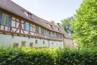 Long half-timbered house with green shutters surrounded by colourful nature, event and wedding
