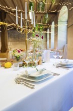 Elegant table decorations with flowers and candlesticks, white tablecloths create a festive