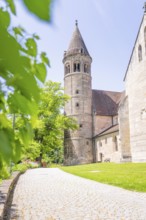 Medieval church tower next to a tree-lined green path on a summer's day, event and wedding location