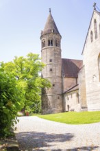 Medieval stone church tower next to a green path in summer light, event and wedding location Lorch
