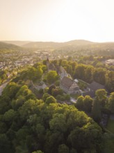 Aerial view of a historic castle surrounded by wooded hills at sunset, event and wedding location