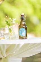 Table with a beer bottle and flower vase outside on a sunny day, event and wedding location Kloster
