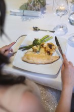 An elegant plate with fish, asparagus and broccoli on a white table, event and wedding location
