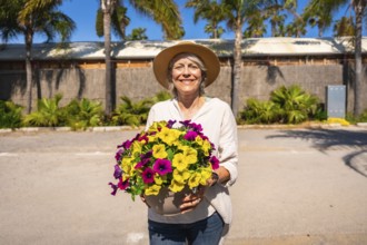 Happy gardener holding a pot of colorful petunias, enjoying a sunny day at the botanical garden