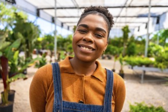 Portrait of a young african american woman working in a greenhouse, smiling confidently amidst lush