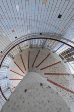 A spiral staircase with colourful tiles and a central concrete pillar, modern architectural design,