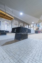 A dark winner's podium stands in an exhibition hall, surrounded by works of art and industrial