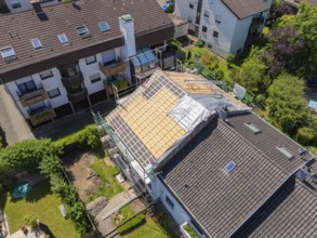 Several houses in the neighbourhood. A roof is under construction with scaffolding, sunny weather,