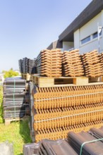 Stack of roof tiles on pallets next to a building outdoors, roof renovation, house construction,