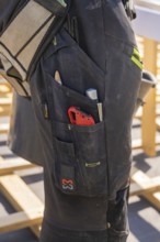 Tools in the pocket of a construction worker's black work trousers, roof renovation, house