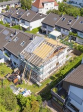 A house with scaffolding and partially new roof, surrounded by a green residential area, roof